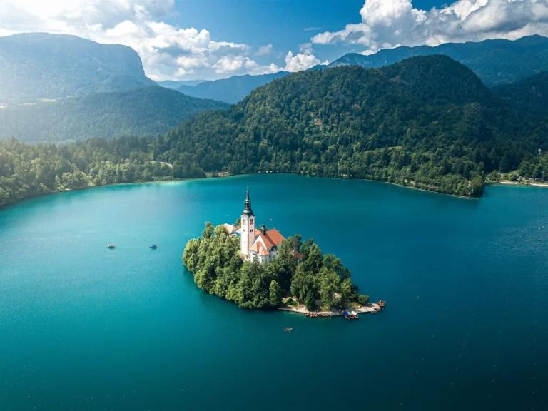 Dronefoto av kirken på øya i Bledsjøen i Slovenia, omgitt av stille vann