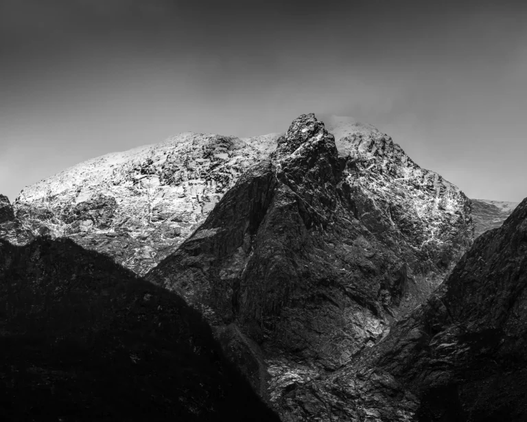 Black and white photograph of a snow-capped mountain peak in Norway against a dark sky.