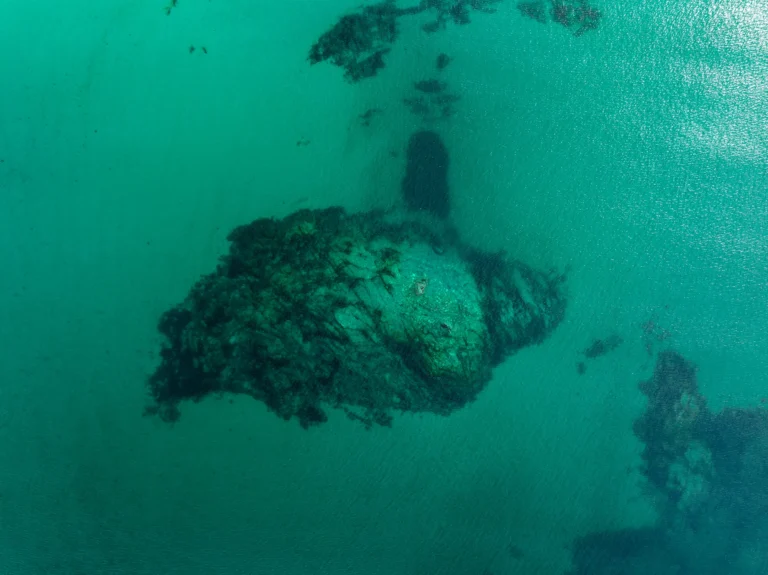 Dronefoto av Hauklandstranden i Lofoten i Norge, med turkist vann som møter en steinete strandlinje