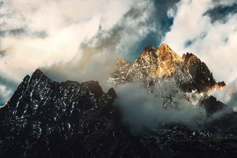 Majestic snow-dusted mountain peak rising above swirling clouds in golden sunlight, fine art landscape photograph from Slovakia
