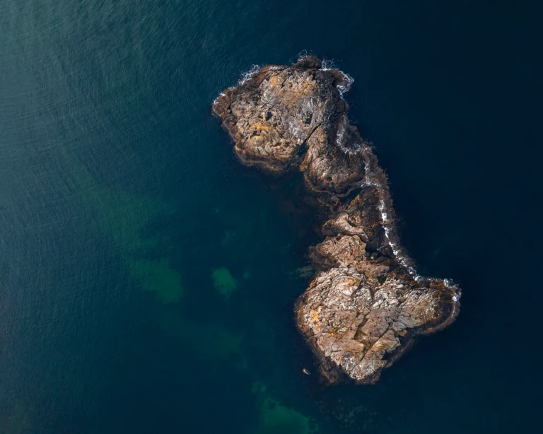 Flyfoto av en kupert klippeøy utenfor norskekysten, omgitt av mørkt hav