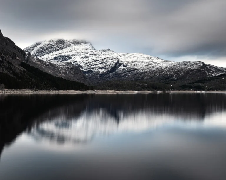 Snow-dusted Norwegian peak partially revealed behind drifting clouds and dark ridgelines