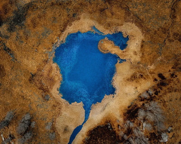 Dronefoto av en sirkulær blå innsjø i et kupert norsk fjellterreng, Benszekely Photography