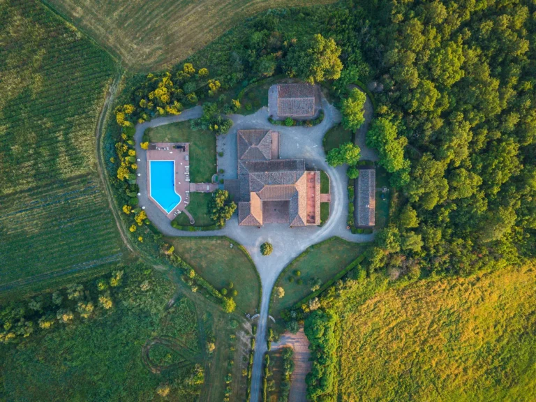 Flyfoto rett ovenfra av et toskansk hotell med basseng og hage i Italia